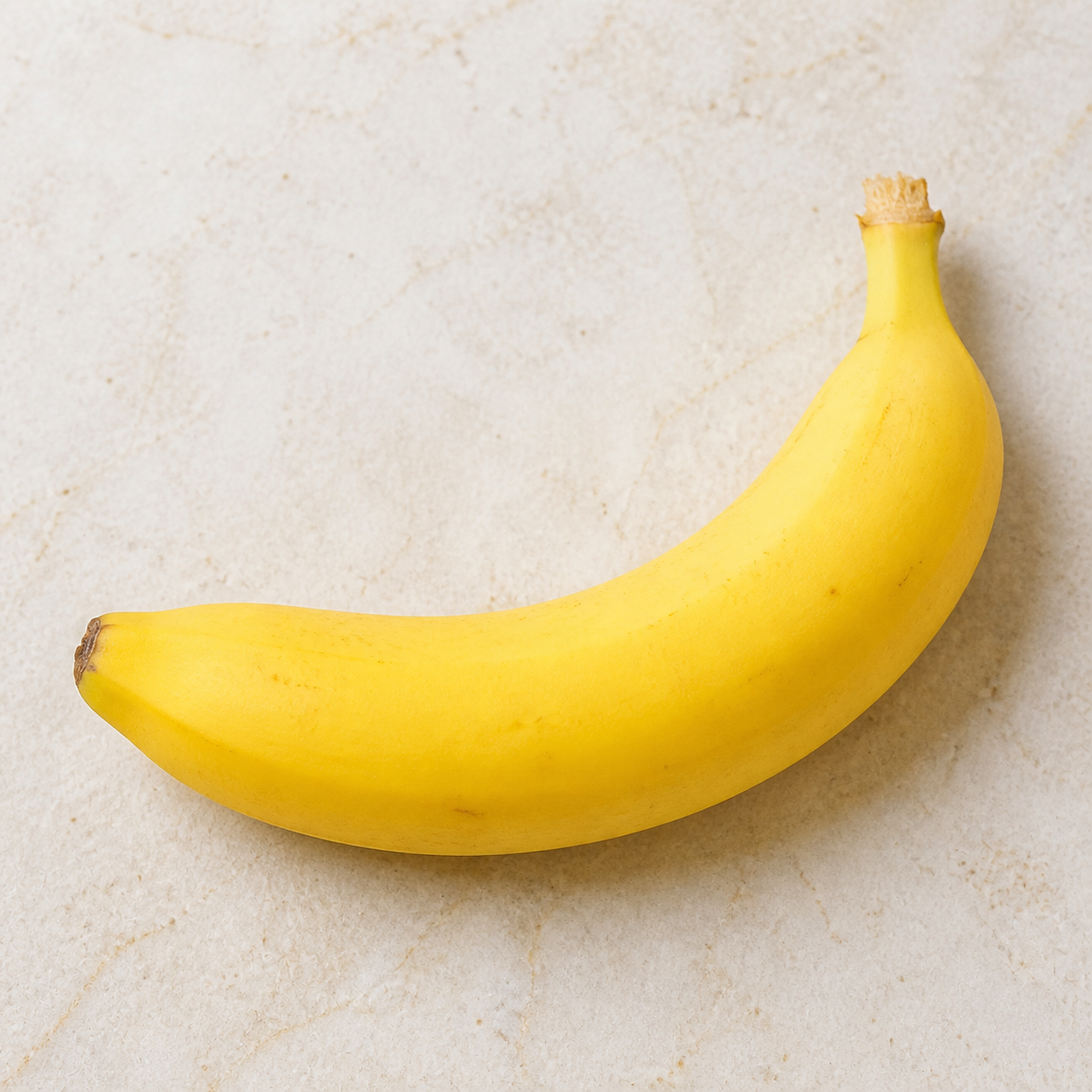 A ripe yellow banana on a light surface